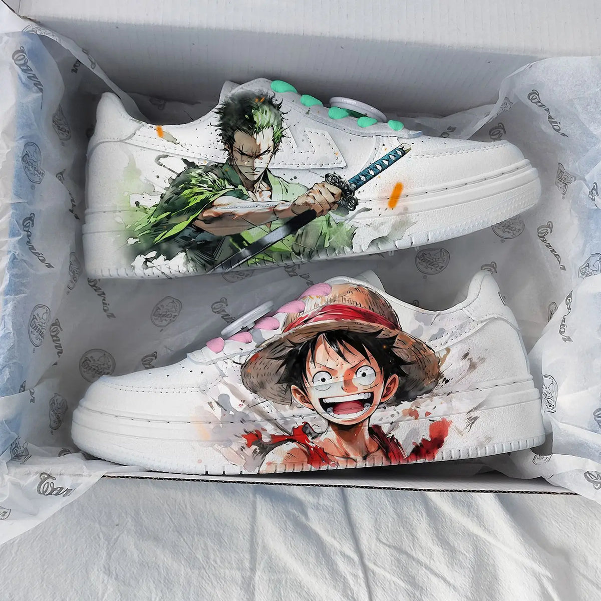 White One Piece sneakers in box with watercolour Zoro artwork on one shoe and Luffy on the other