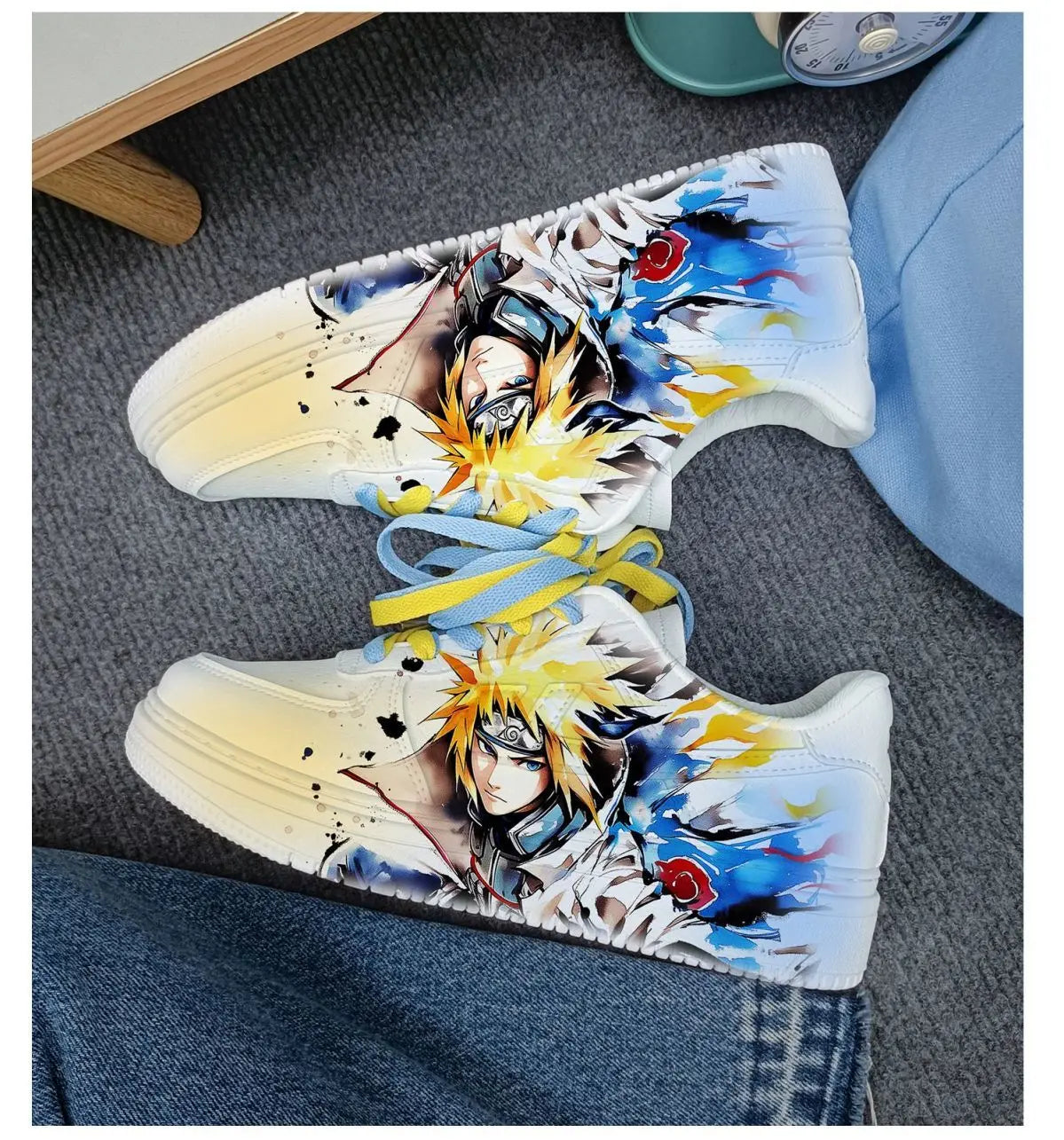 Overhead view of white Naruto Minato low-top sneakers with blue and yellow laces tied between them