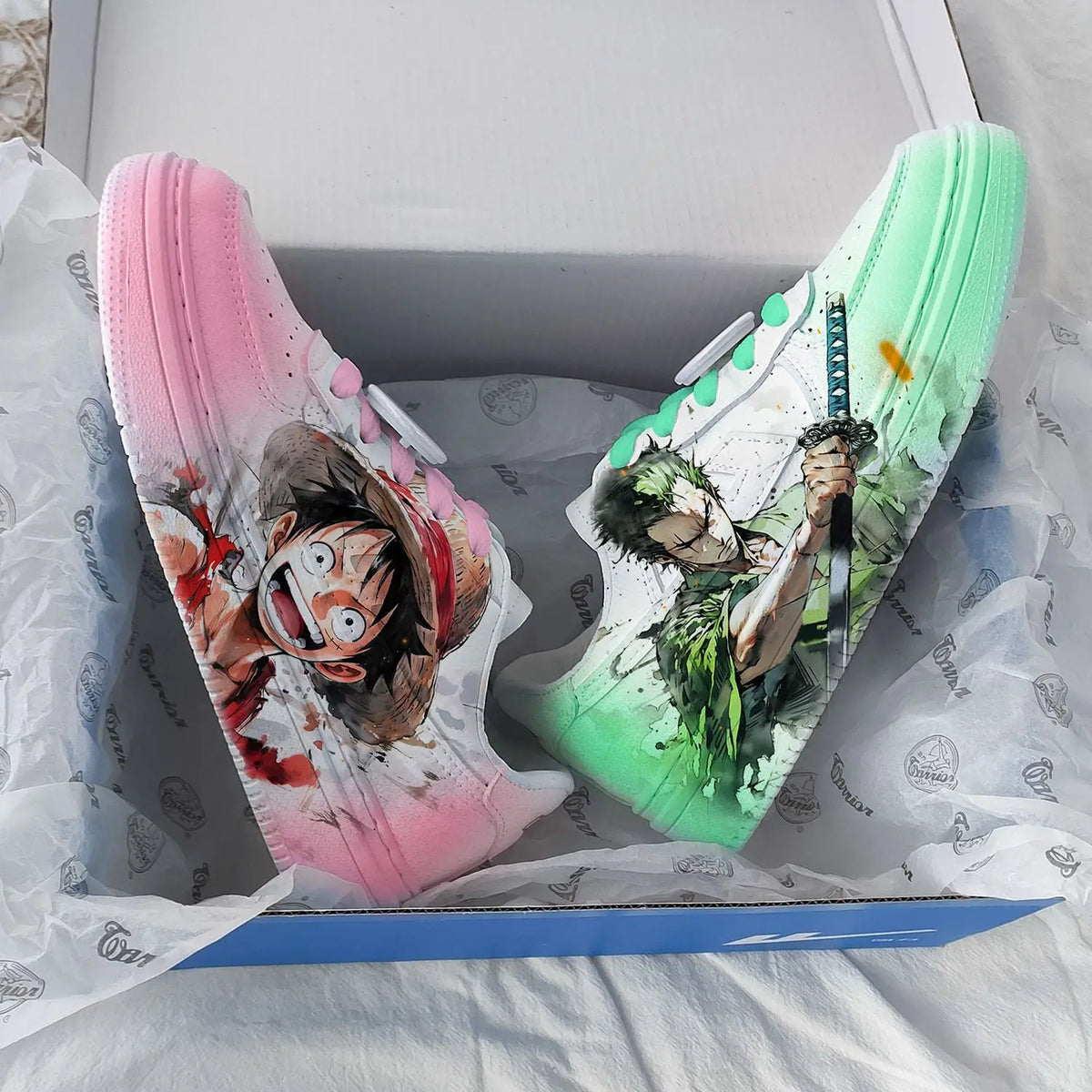 Top view of One Piece gradient sneakers with pink Luffy shoe and mint green Zoro shoe in box
