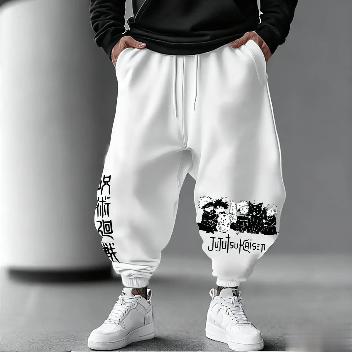 White Jujutsu Kaisen joggers with black chibi Jujutsu Kaisen characters and logo on the leg, worn with white sneakers